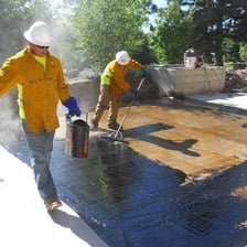 Road workers applying dark paving material to a road.