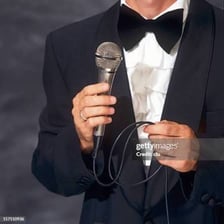 A master of ceremonies speaking into a microphone at an awards event.