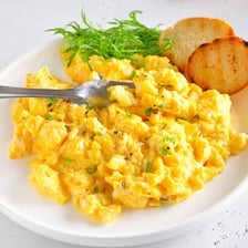 A hotel breakfast buffet tray filled with scrambled eggs