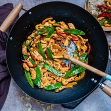 A rounded wok containing vegetables being stir-fried.