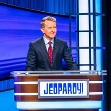 Ken Jennings standing at the podium while hosting Jeopardy!