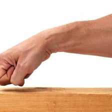 A hand knocking on a wooden table as a gesture for luck
