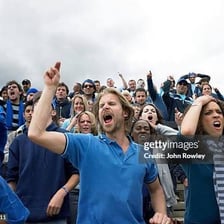 Soccer fans celebrating and shouting after a goal