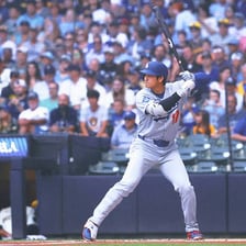 A baseball batter standing at home plate facing the pitcher