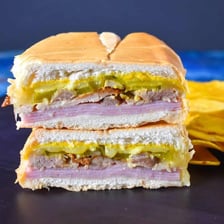 A sliced Cubano sandwich contains ham and other fillings.