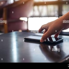 A hand takes a phone from a tabletop.