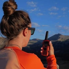 A person communicating with a handheld walkie-talkie.