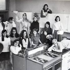 Students learning cooking skills in a home economics classroom.