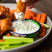 Buffalo chicken wings served beside a bowl of blue cheese dip.
