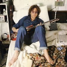 A portrait of musician John Lennon holding a guitar