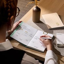 A person writing plans in a notebook.