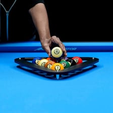 A pool table with billiard balls arranged in a triangular rack