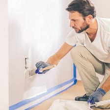A paintbrush applying a layer of paint to a wall