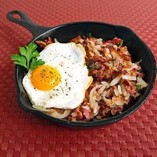 A serving of corned beef hash beside hash browns.