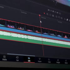 An audio waveform aligned with video clips on an editing timeline.