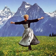 A yodeler standing in a mountainous Alpine landscape.