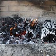Gray ash and partially burned wood inside a fireplace
