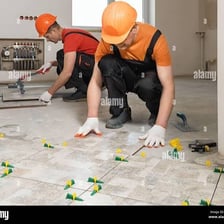 A worker installing ceramic tiles on a floor