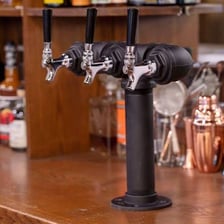 A row of beverage taps mounted behind a bar.