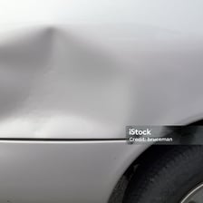 A visible dent in a vehicle's fender