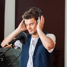A musician listening closely to music through headphones.