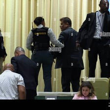 A person being escorted away from an event by security personnel