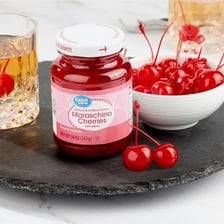 A cherry with its stem next to a cherry without one