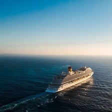 A cruise ship traveling across open water away from the coast.