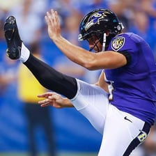 An American football player kicking a ball downfield in a punt.