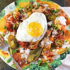 A plate of chilaquiles made with tortilla pieces and salsa