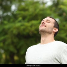 A person taking a deep breath outdoors.