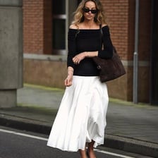 A woman wearing a skirt that falls around mid-calf.