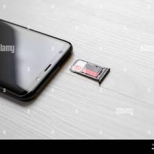 A removable SIM card next to a smartphone