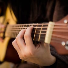 A person strumming the strings of an acoustic guitar.