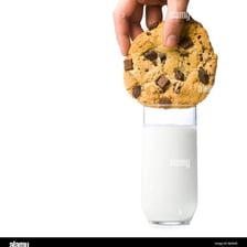 A cookie being dipped into a glass of milk