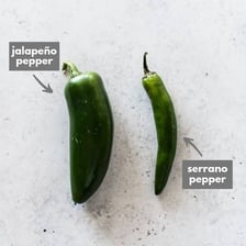 Fresh serrano and jalapeño peppers shown together for comparison.