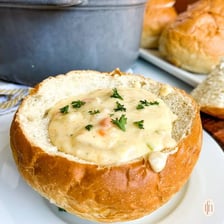 A bread bowl filled with clam chowder at a waterfront wharf.