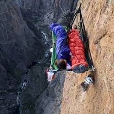 A climber resting on a narrow rocky ledge