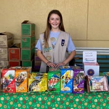 A Girl Scout troop displaying cookie boxes