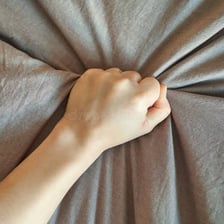 A hand touching textured fabric to sense its surface.