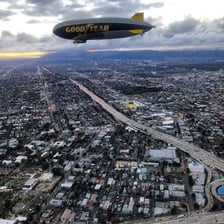 A blimp flying above the ground.