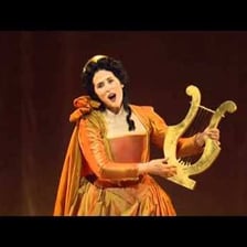 An opera singer performing a solo onstage with an orchestra.