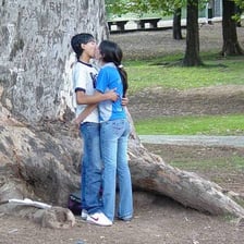 A couple kissing outdoors in a public park