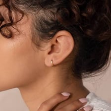 A small hoop earring fitted close around an earlobe.