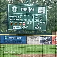 A baseball batter celebrating a grand slam with a scoreboard showing runs.