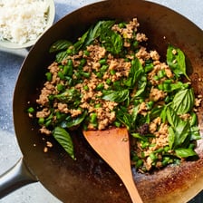 A serving of Thai pad krapow gai garnished with fresh basil leaves.