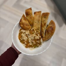 A piece of naan flatbread served with a curry dish.