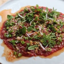 A plate of thinly sliced raw beef carpaccio with garnish