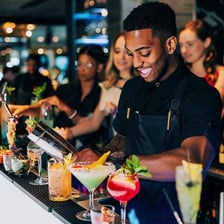 A bartender serving a round of drinks at a bar