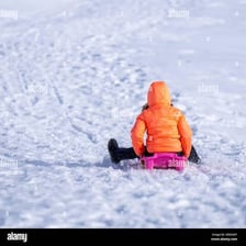 A child riding a sled down a snowy hill.